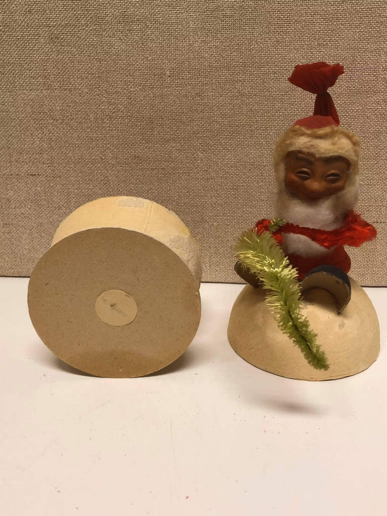 TOMTE sittande på gömma, papermaché, 1900-första hälft.