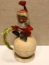 TOMTE sittande på gömma, papermaché, 1900-första hälft.