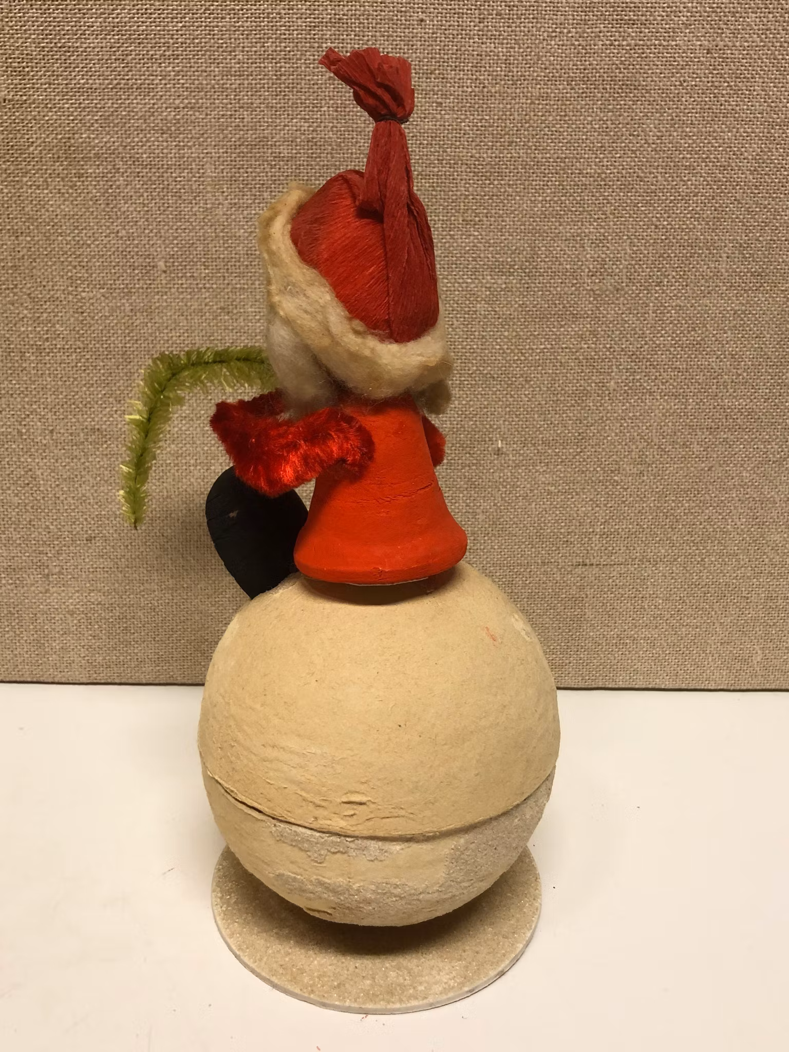 TOMTE sittande på gömma, papermaché, 1900-första hälft.