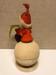 TOMTE sittande på gömma, papermaché, 1900-första hälft.