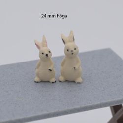 Kanin som sitter och har hand på magen 24 mm hög