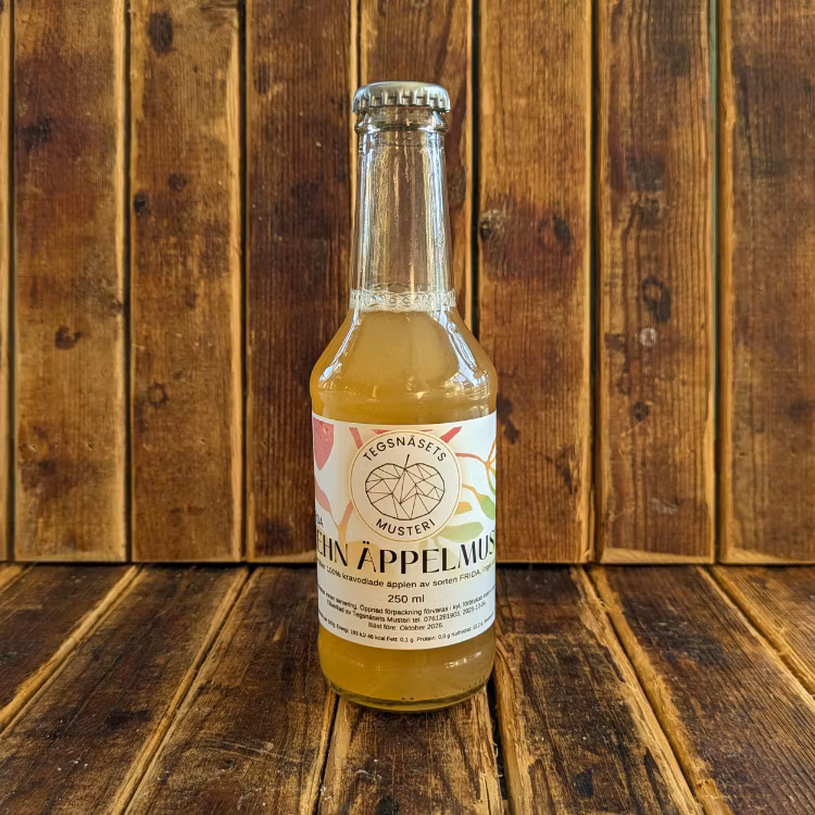 Äppelmust i flaska från Tegsnäsets musteri står med träbakgrund