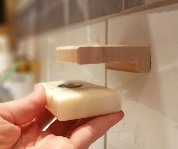 En hand som visar hur man sätter in en magnet i tvålen för att sedan fästa den magnetiskt på tvålhållaren