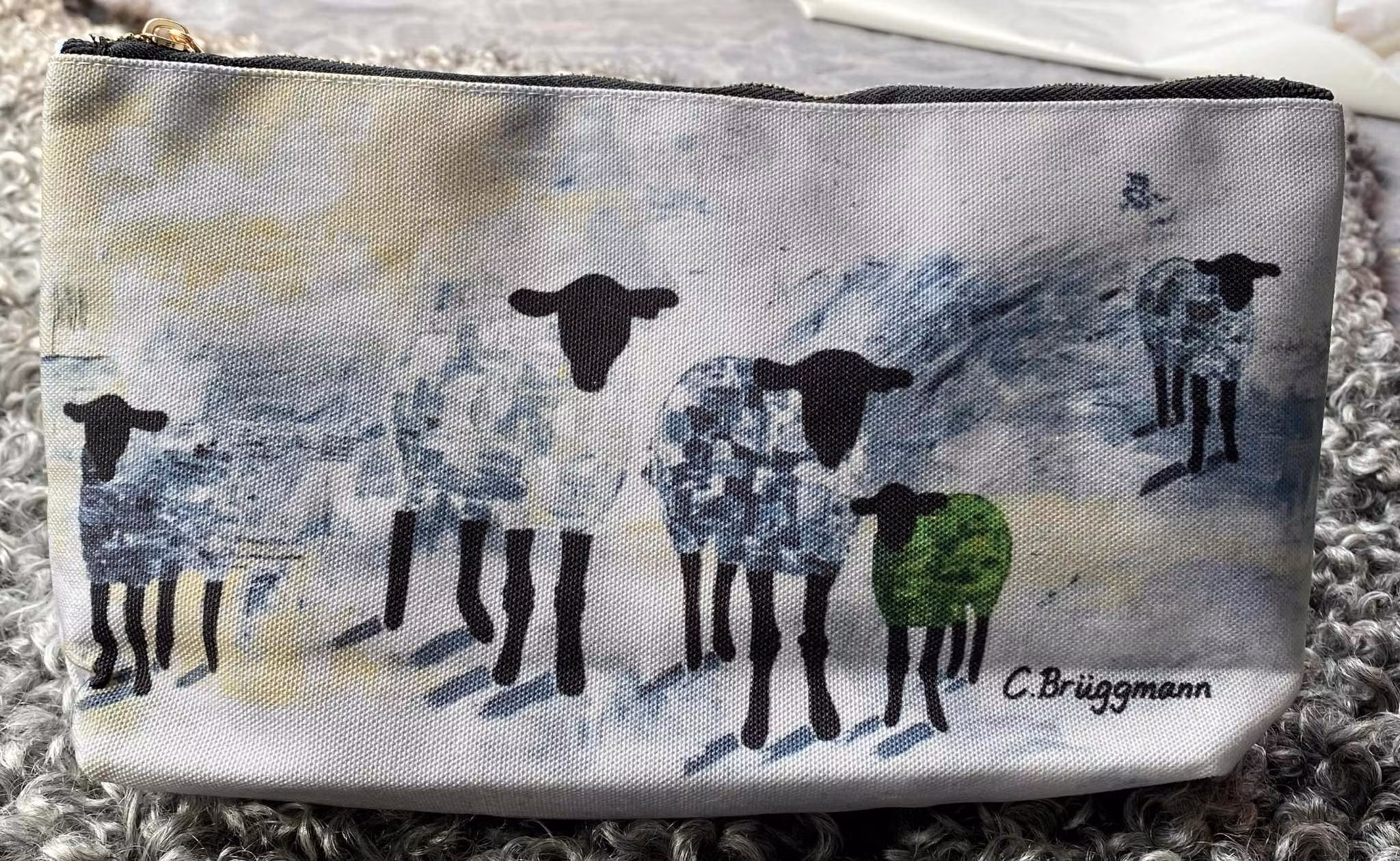 Toalettväska i grönt, grått och beige fårmotiv. Gotlandsfår tolkade av konstnär C.Brüggmann.