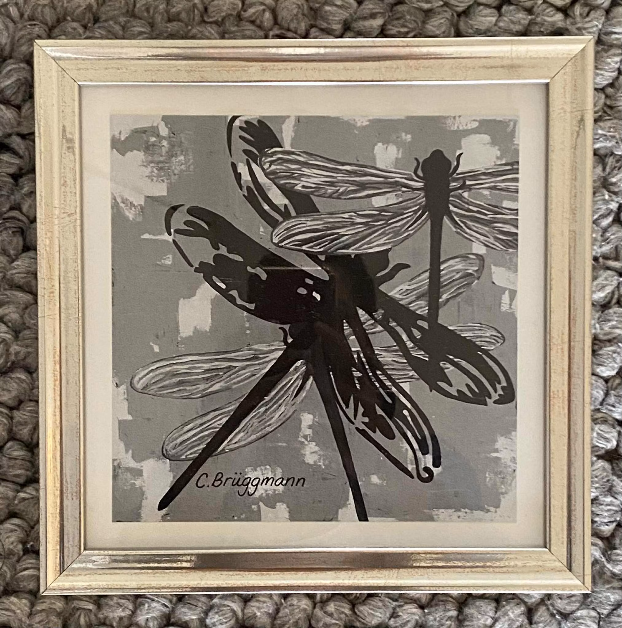 Liten tavla med trollsländor i svart-vitt och grått. Inramad i silvrig ram och redo att hängas upp.