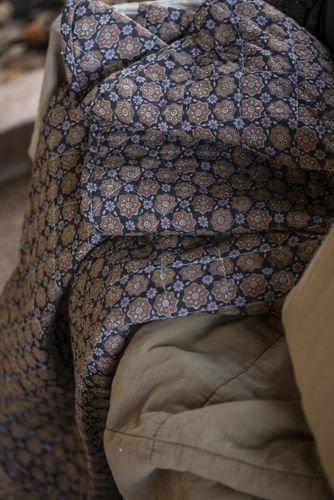 Quiltad pläd i svart med blommor i rostfärg