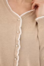 Beige stickad kofta med pärlknappar och volang