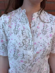 Cremevit blus med gröna och rosa blommor