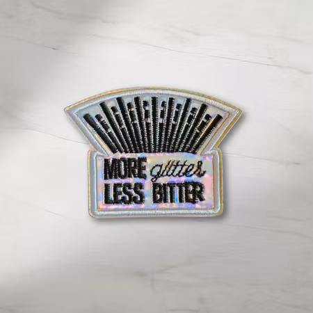 More Glitter Less Bitter tygmärke