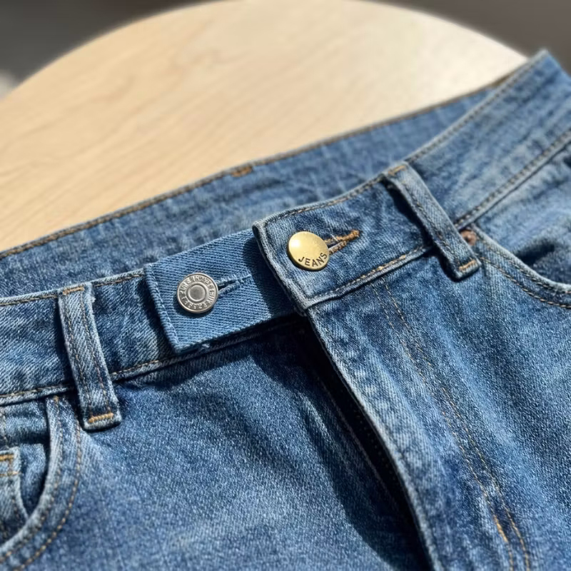 Jeanslinning med befintlig knapp, denimförlängare och förlängarens knapp.