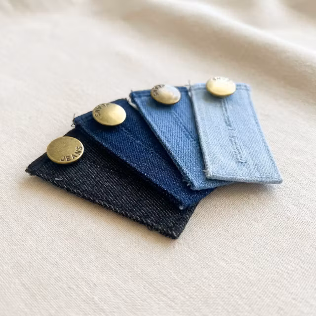 Fyra midjeförlängare i olika denimnyanser på ljust tyg.