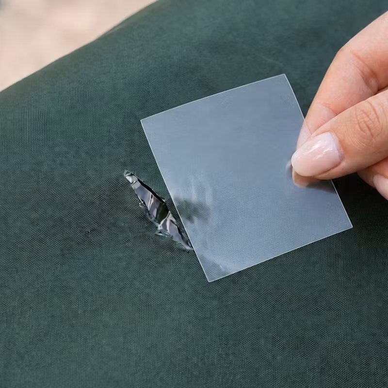 En hand håller en transparent lapp över en reva i grönt material