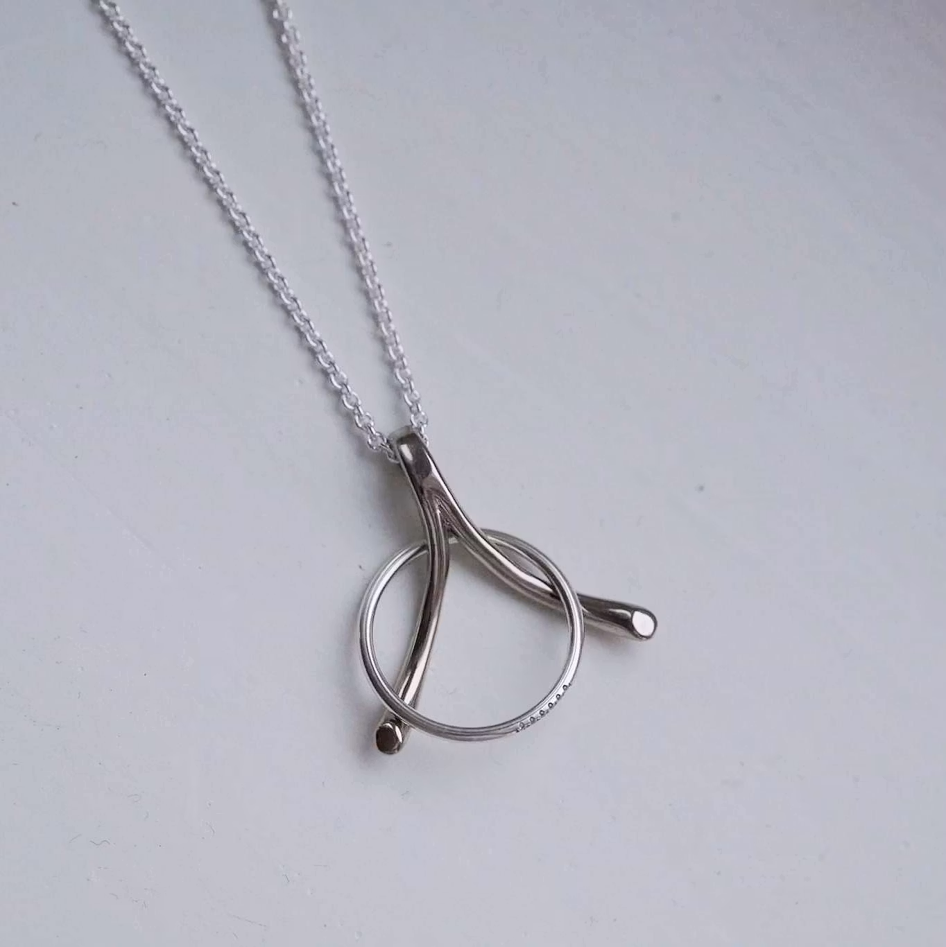 "Wishbone" ring holding pendant in white gold