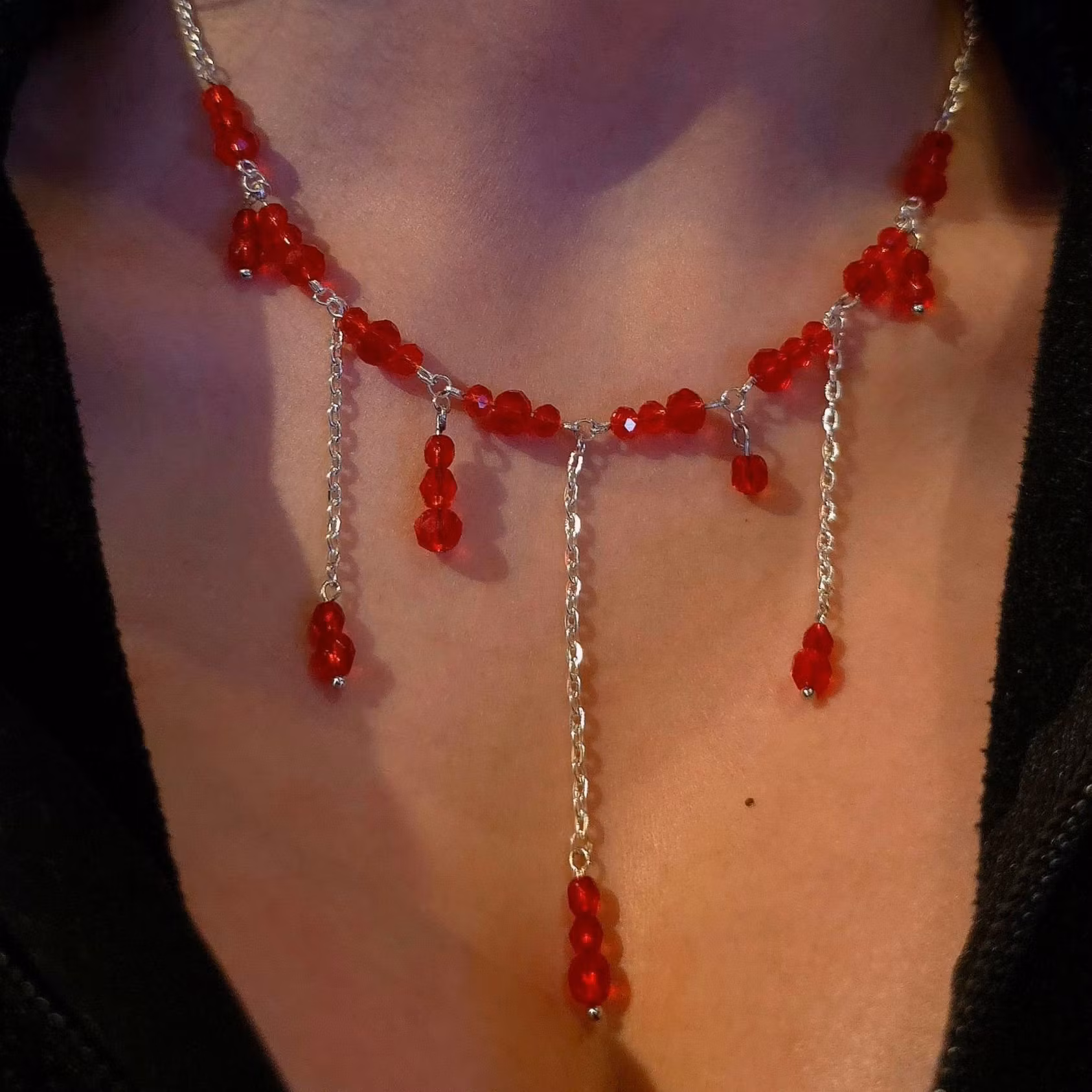 Handgjort halsband med röda pärlor som ser ut som bloddroppar som rinner nedåt i olika nivåer