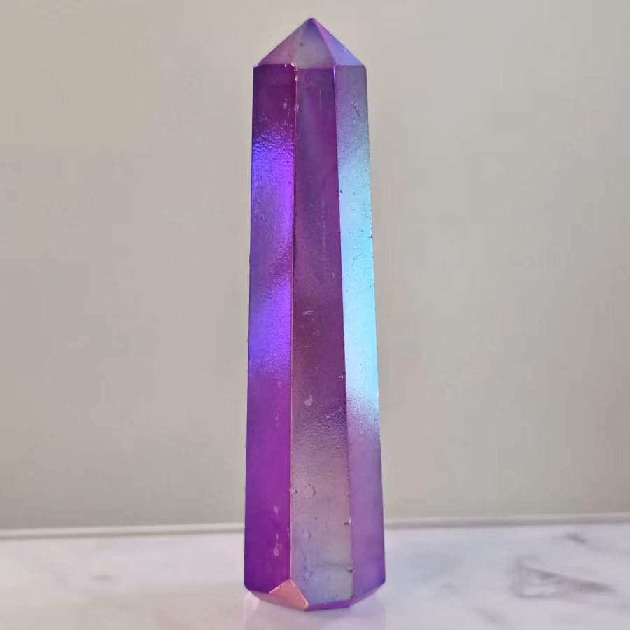 Torn av Bergkristall med lila Aura färgbehandling. Auran skapas genom att klar bergkristall behandlas med guldånga under hög värme, vilket ger den sitt karakteristiska iriserande skimmer