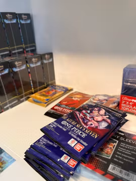 Japanska One Piece-boosterpaket bredvid Ultra Pro-toploaders och sleeves.