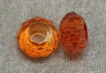 Facetterad orange glasrondell med stort hål