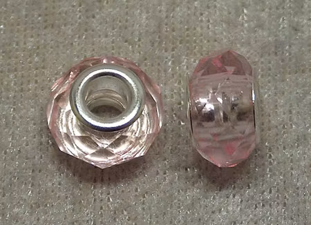 Facetterad transparent rosa glasrondell m stort silverfärgat hål